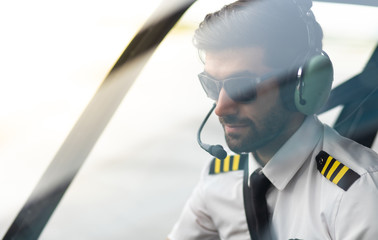 Pilot with headset starting the controls in cockpit helicopter. Helicopter pilot sitting in the...