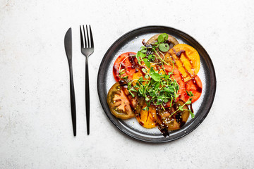 Fresh colorful tomatoes salad with balsamic vinegar on a plate, top view