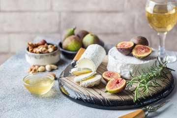 Obraz na płótnie Canvas Fresh goat brie cheese with truffle and white mold on cheese platter with figs and honey