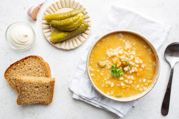 Soup with pickled cucumbers and pearl barley - rassolnik on white background, top view