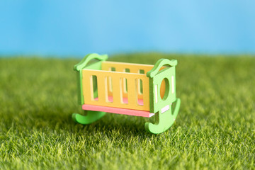 An empty wooden crib stands on the green grass in the courtyard of the house.
