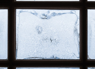 Frost patterns on window glass framed with dark wood