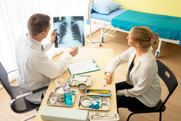 Obraz premium Doctor explaining lungs x-ray to women patient in clinic or Doctor in the office examining an x-ray and discussing with a patient