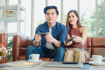 Young couple having fun playing videogame at home.