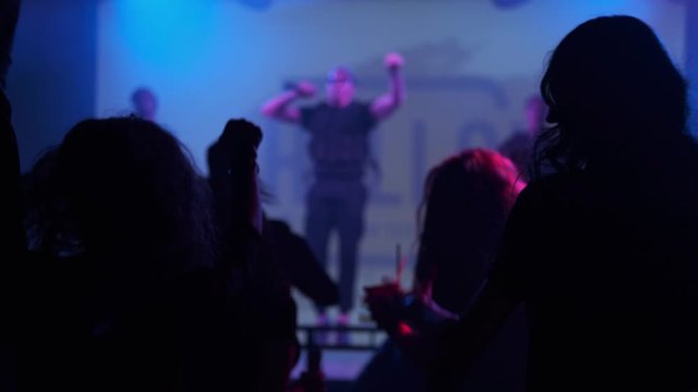 A group of people wave their hands during a flash mob at a light show party