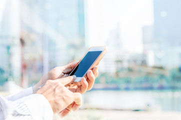 5G technology world wide web connecting.close up business man using hand typing smartphones and touch screen working search with app devices outdoor in city with sunrise and building background.