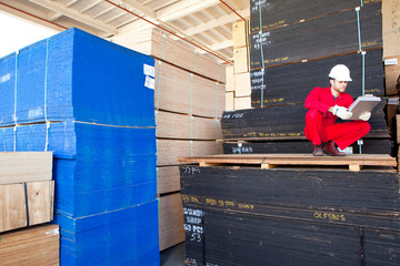 Fototapeta premium Hispanic worker inspecting tablet PC in timber warehouse