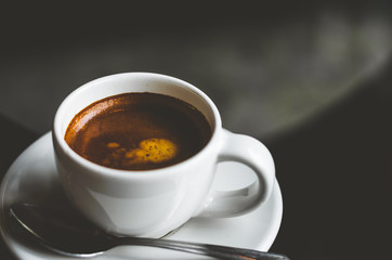 close up modern hot black coffee the cappuccino on wood background with coffee bubble foam pattern and texture in white cup looking and feel so delicious on glasses table in coffee shop.