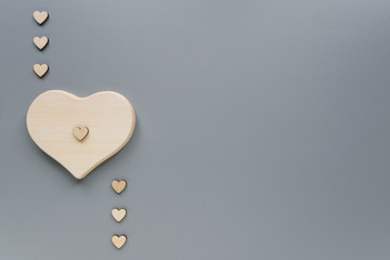 Hearts of different sizes made of eco-friendly materials. Wooden hearts for Valentine's Day. Hearts on a grey background with copy space