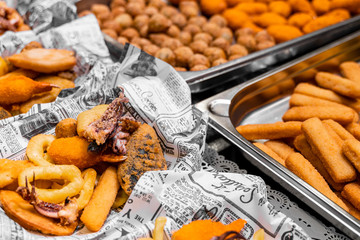 Fried snacks in paper cups on the city market, fast street food