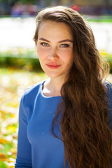 Young beautiful brunette woman in blue dress in autumn park