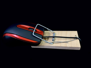 A mouse from a computer in a mousetrap, on a black background. Concept: computer addiction