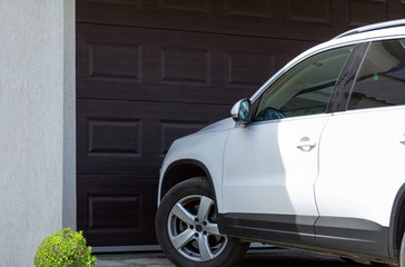 White car in front of modern house waiting to enter in the garage with large garage door