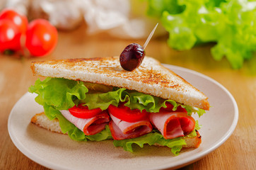 Ham sandwich on a plate on the table. Quick snack. Fast food.