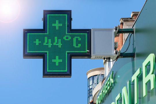 Thermometer in green pharmacy screen sign displays extremely hot temperature of 44 degrees Celsius during heatwave in summer