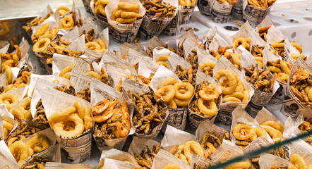 Fried snacks in paper cups on the city market, fast street food