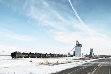 A row of oil tank cars parked at a small rural grain terminal in a deserted and quiet Canadian...