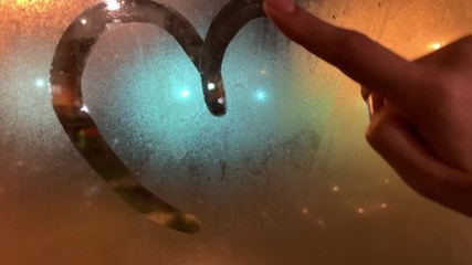 Close up of female finger drawing heart shape on wet window against street light - Powered by Adobe