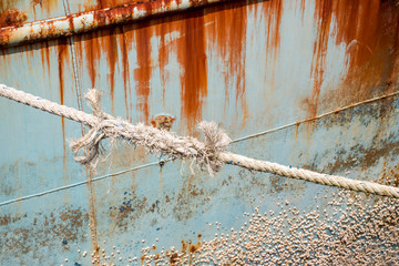 closeup on an old weathered rope white with a knot securing a fishing boat
