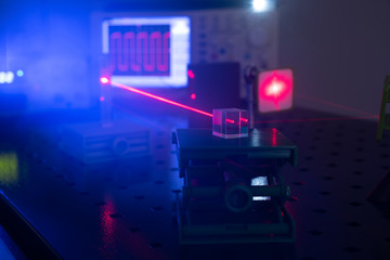 Experiment in optic lab with laser device. Red laser on optical table in physics laboratory
