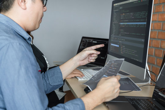 Two professional programmer cooperating and working on web site project in a software developing on desktop computer at company, codes and typing data code, Programming with HTML, PHP and javascript