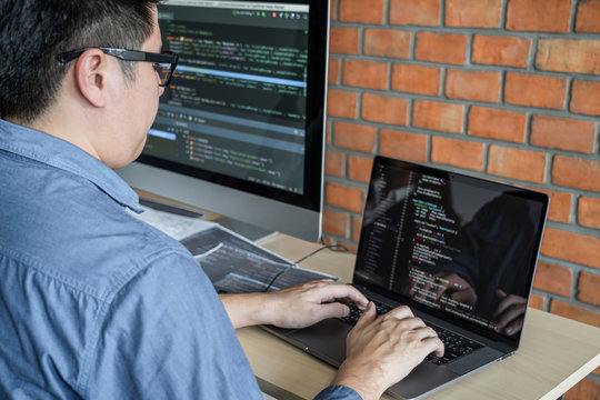 Young Professional programmer working at developing programming and website working in a software develop company office, writing codes and typing data code, Programming with HTML, PHP and javascript