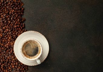 Cup of tasty coffee and beans on a stone background. Top view with copy space for your text.