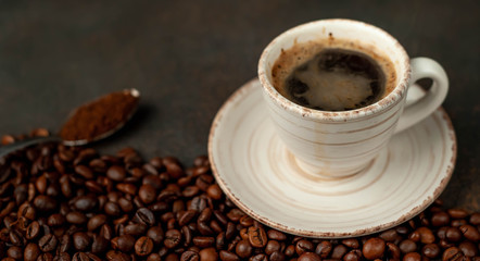Cup of tasty coffee and beans on a stone background. Top view with copy space for your text.