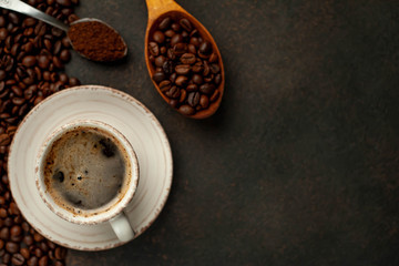 Cup of tasty coffee and beans on a stone background. Top view with copy space for your text.
