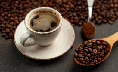 Cup of tasty coffee and beans on a stone background. Top view with copy space for your text.