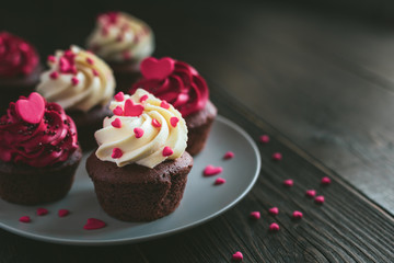 Valentine cupcakes in white and red colors, served on the plate and decorated with sweet hearts.