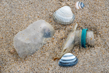 Old partly broken down plastic bottle, non-biodegradable waste washed ashore on sandy beach along the North Sea coast