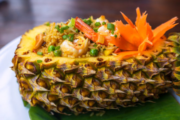 Close up Thai royal pineapple fried rice. Fried rice with shrimps served in a pineapple on wood table.