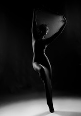 Slim girl wearing a white bodysuit dances a modern avant garde dance, covering her body with elastic transparent fabric. Artistic, conceptual, monochrome and creative design. Silhouette  photography.