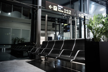 Chairs in the airport waiting room near the boarding gates. Empty room with no body. Signs of departure gates.