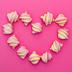 Zephyr lined in a heart shape on a white background. Flat lay. Top view. Pink sweet homemade zephyr or marshmallow. Colorful meringues on white. top view dessert image.