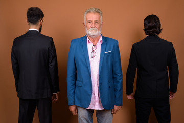 Three multi ethnic bearded businessmen together against brown background