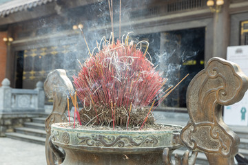 many of burning incense sticks in joss stick burner pot with smoke in the Chinese temple.