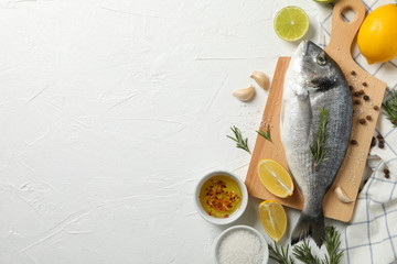 Cutting board with Dorado fish and cooking ingredients on white background, space for text