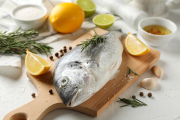 Cutting board with Dorado fish and cooking ingredients on white background, close up