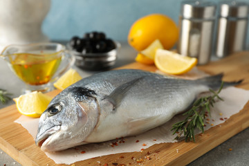 Cutting board with Dorado fish and spices on grey background, close up