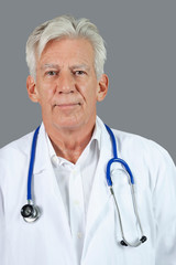 Portrait of confident senior doctor with stethoscope around neck over gray background