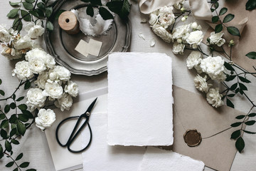 Moody wedding table mockup scene. Stationery composition with fading white rose flowers, silver...