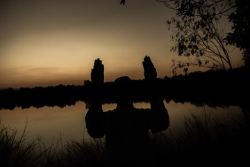 Fototapeta na wymiar Silhouette Young asian muslim man praying on sunset,Ramadan festival concept