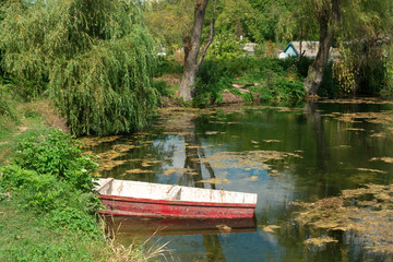 Old fishing boat on the pond near village 