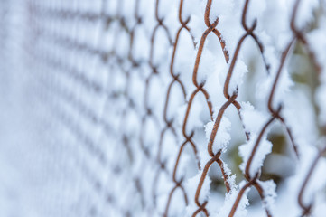 Pattern of old rusty fence covered in frost and snow