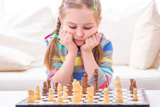 Adorable female child is in deep thought about chess`s ultimate winning strategy