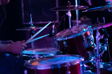 Fototapeta na wymiar Artistic man playing on professional drum set on the stage