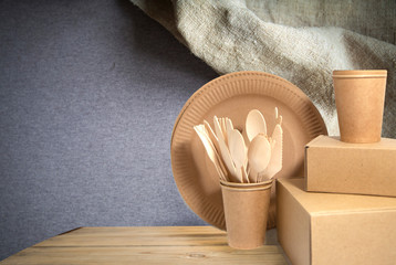 .Crockery made from eco kraft paper, paper cups, crockery, bag, fast food containers on a wooden, concrete wall background. Zero waste. Close-up.