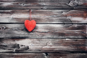 A red heart hanging on an old vintage shabby wooden wall in brown-white. Greeting card. Valentine's card.
